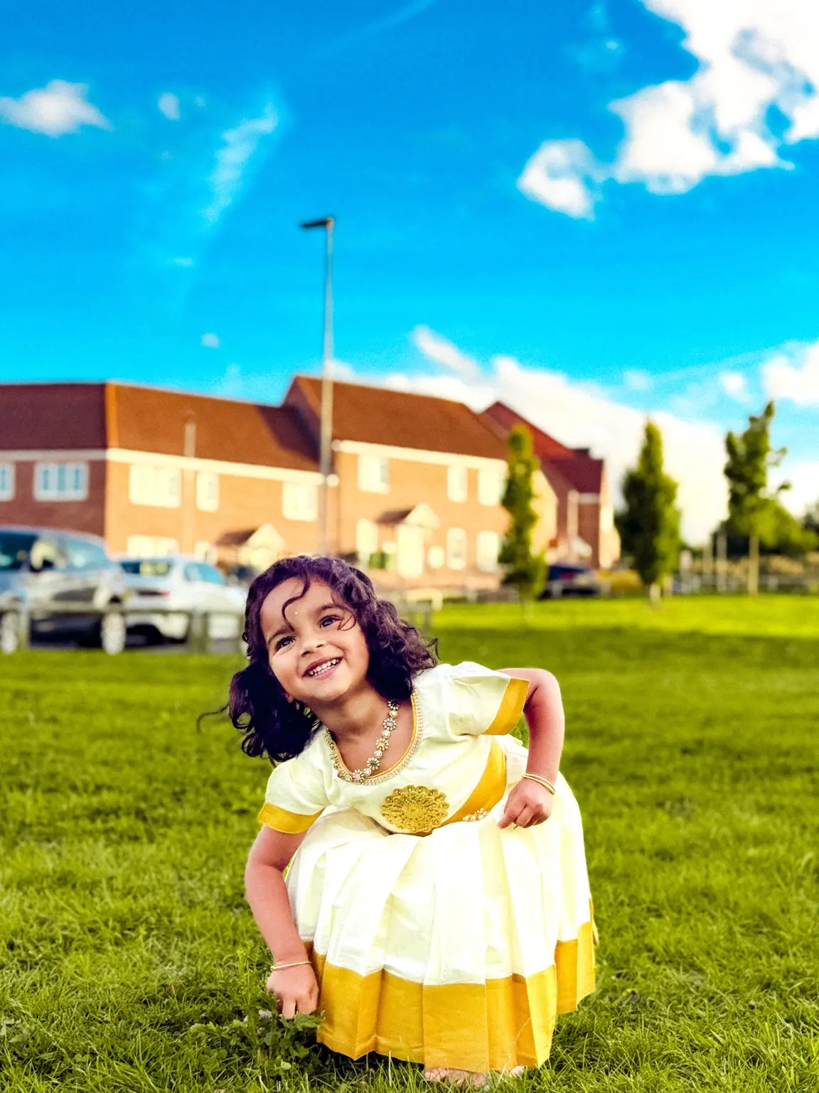 Joyful child in an ivory and gold dress on grass