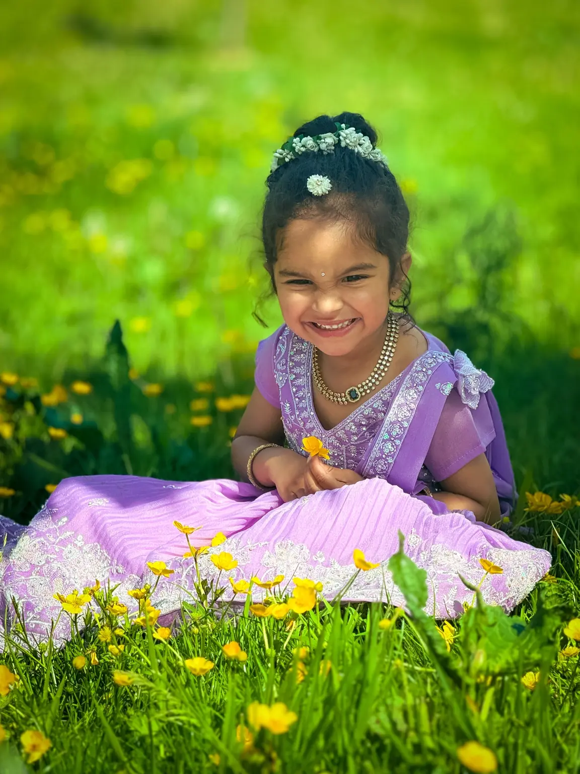 Smiling child in a purple dress among yellow flowers