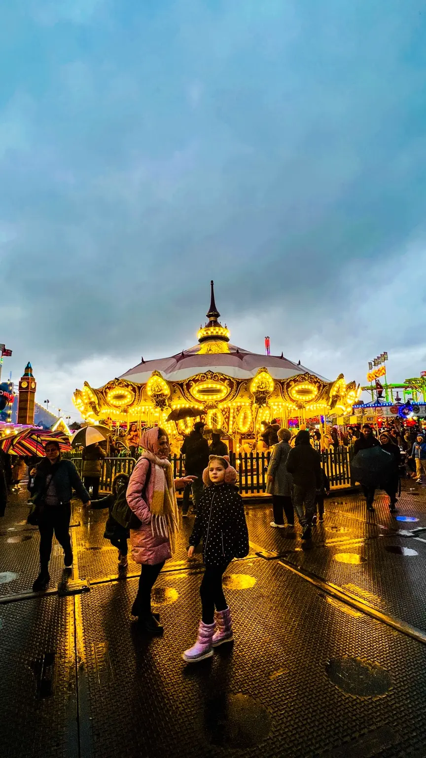 Illuminated fairground carousel on a rainy evening